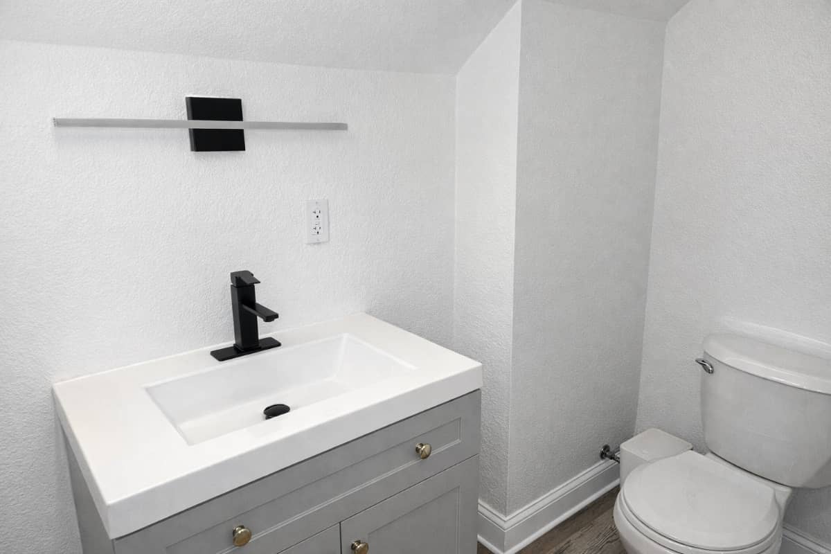 bathroom remodel with new toilet, cabinets, and mirror